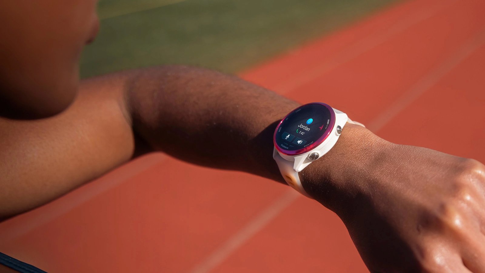 The Garmin Forerunner 570 on a woman's wrist at the track, the screen showing her taking a phone call.