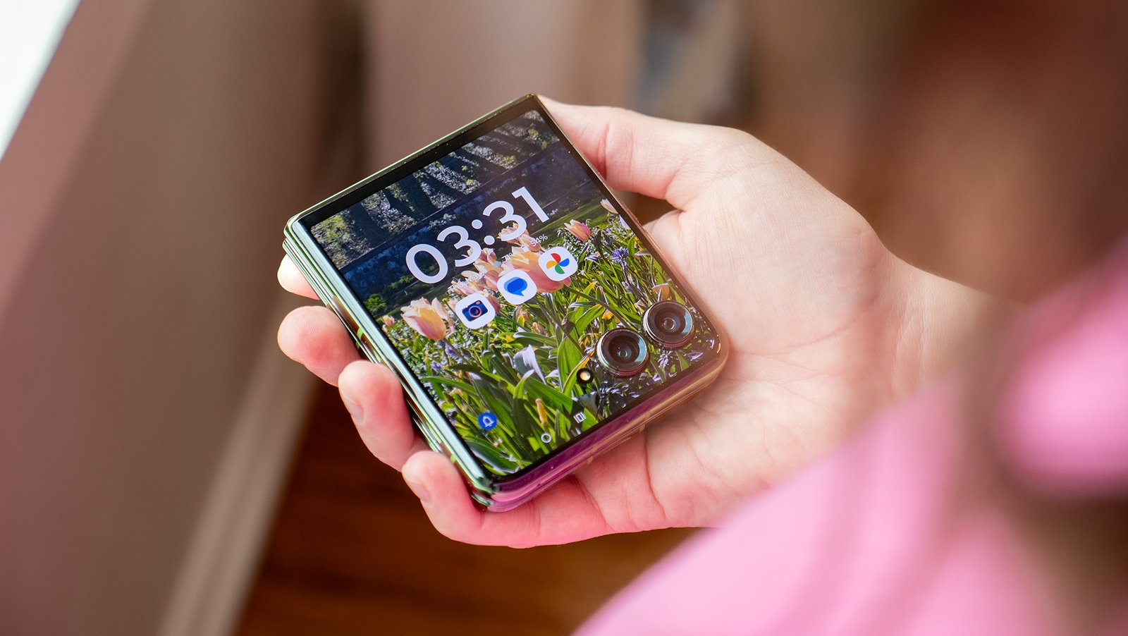 Holding a Motorola Razr Plus 2024 while it's closed with its cover screen illuminated and unlocked