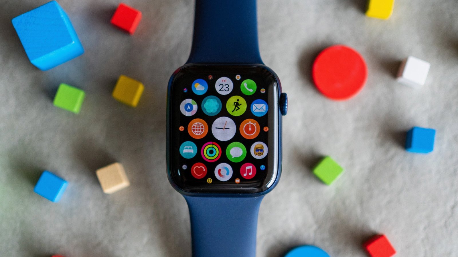 The Apple Watch Series 6 on a felt floor with colorful blocks, displaying app icons.
